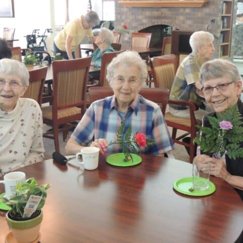 three women smiling holding flowers at Hill Street Place