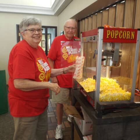 two people getting popcorn out of the popcorn machine