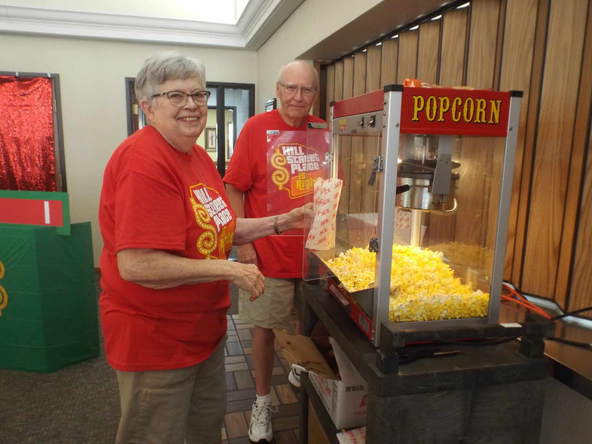 two people getting popcorn out of the popcorn machine