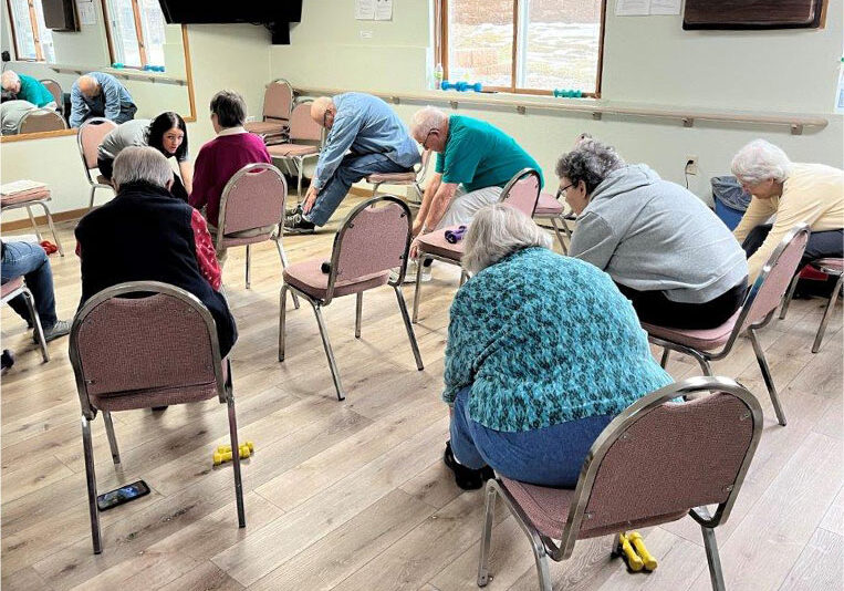 group of elders doing chair yoga with instructor